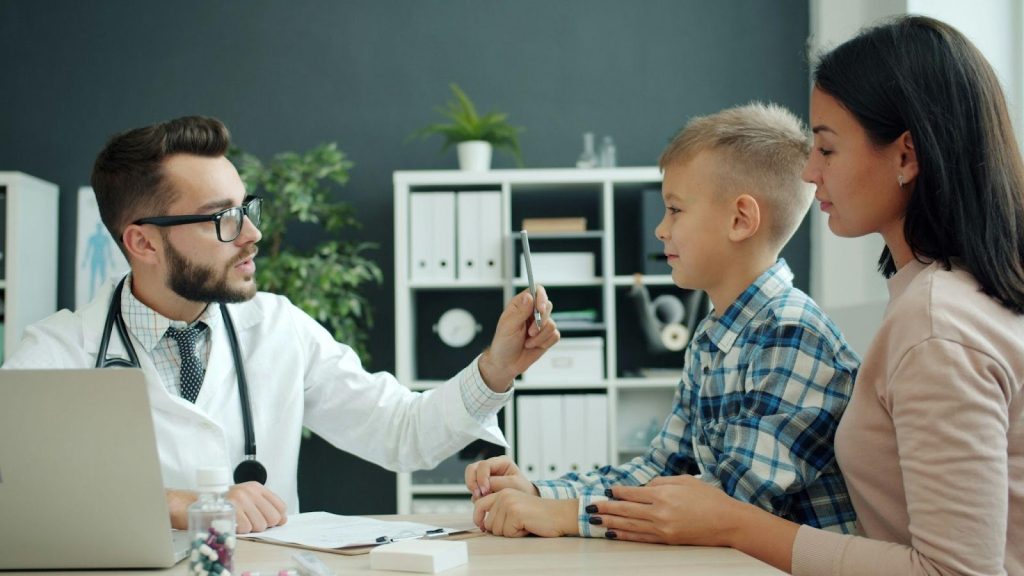 Healthcare provider consulting with a young patient and parent in a clinic, illustrating personalized care supported by efficient scheduling tools.