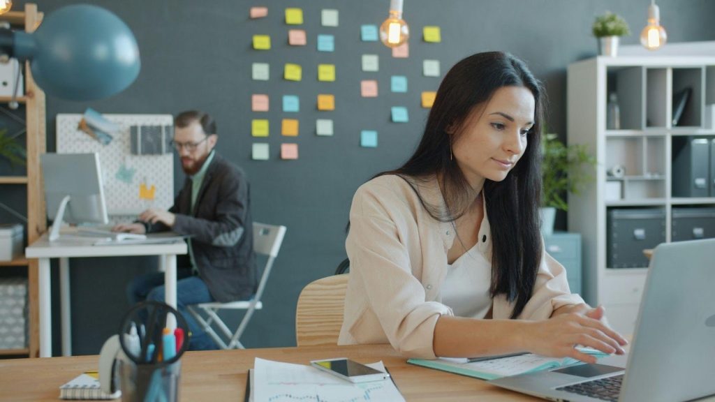Digital marketers working on a laptop and desktop in a modern office.