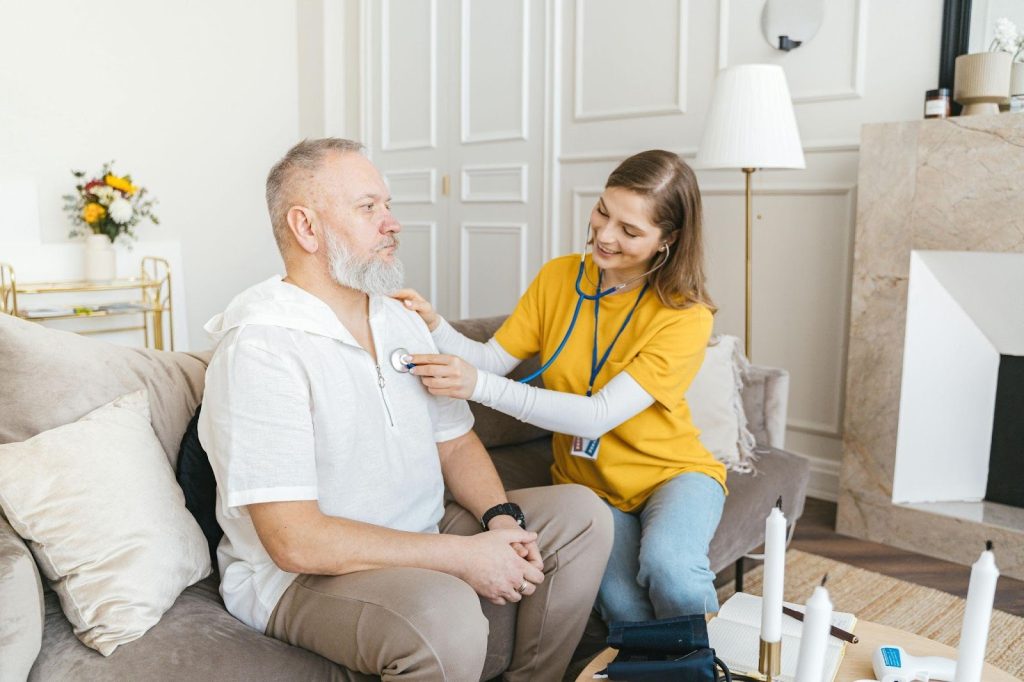 Live-in caregiver checking heart rate of an older man during an in-home care visit.